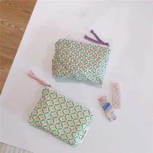 Close-up of floral cotton pouches with zippers and woven pullers in pink and purple colors