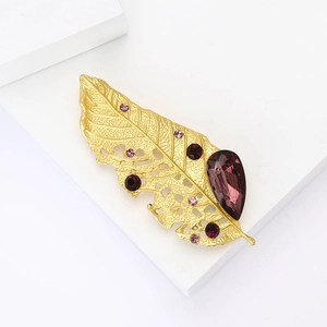 Elegant gold-tone leaf brooch with purple water-drop rhinestones on a white background