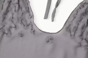 Gros plan détaillé du décolleté dos nu gris avec mousseline transparente et motifs