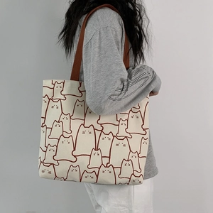 Detail of canvas tote bag with brown straps and cute red-lined cat prints