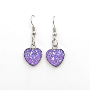 Macro view of purple heart-shaped earrings with sparkling sequins and silver hooks