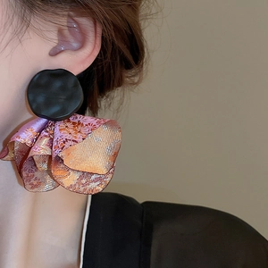 Close-up of floral pleated fabric earrings with vintage textured metal studs on a model