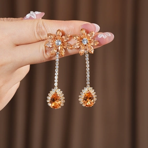 Detailed close-up of vintage flower earrings with orange stones and zircon in golden finish