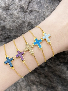 Detailed shot of five colorful druzy cross bracelets with golden snake chains on wrist