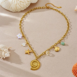 Detail einer vergoldeten Kette mit Muscheln und Sternanhängern auf Sandhintergrund