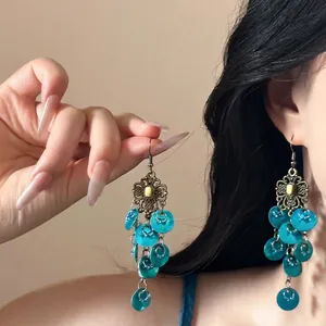 Detail of vintage bohemian shell tassel earrings with bronze hollow floral patterns
