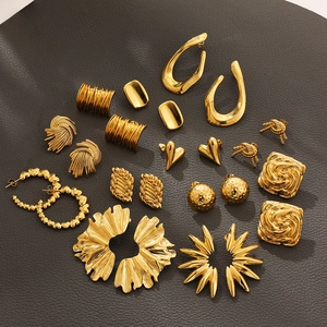Flat lay of multiple 18K gold petal and leaf earrings set on textured dark background