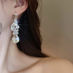 Close-up of sparkling silver teardrop rhinestone earrings worn by a model
