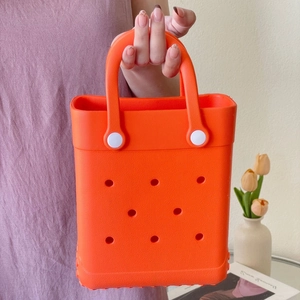 Detail of bright orange EVA beach bag with circular cut-outs and white button accents