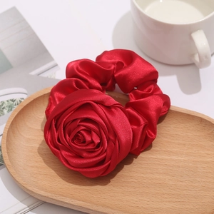 Elegant red satin rose scrunchie on a wooden tray with a vintage French aesthetic