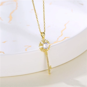Macro shot of gold key pendant with sparkling zircons on marble display tray