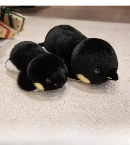 Gros plan détaillé de peluches pingouins noires de tailles variées sur un tapis blanc