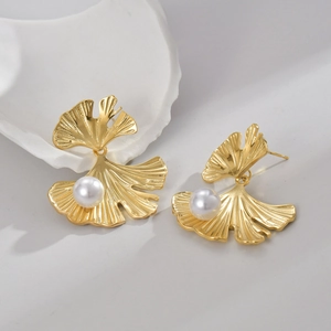 Macro detail of French vintage golden ginkgo leaf earrings with elegant white pearls