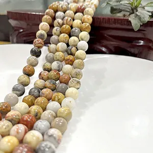 Polished natural tiger eye and jade beads on a white ceramic plate with zen decor