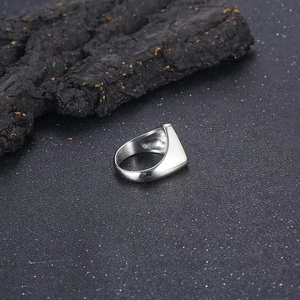 Close-up of polished silver stainless steel signet ring on dark textured stone