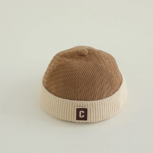 Close-up of baby miki hat featuring brown corduroy texture and white knit trim with C logo