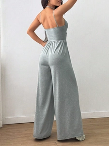 Detail of the backless silver grey jumpsuit with thin straps and shiny texture