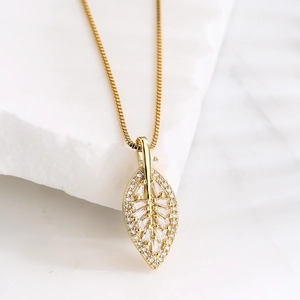 Micro shot of a gold leaf pendant necklace with micro-paved zircons on marble stone