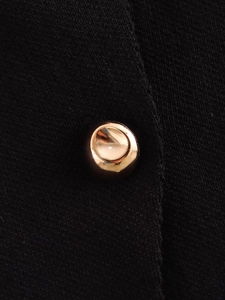 Nahaufnahme der schwarzen Strickstruktur mit einem edlen runden goldfarbenen Metallknopf