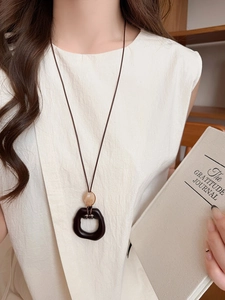 Detail of vintage acrylic pendant necklace worn by a model in a warm setting
