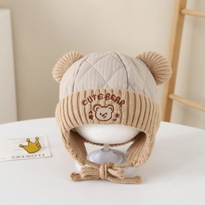 Detail of embroidered bear character and quilted texture on a warm winter earflap hat