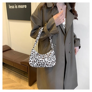 Femme élégante en manteau vert portant un sac sous le bras en toile à motif léopard