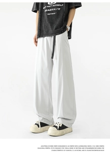 Detalle de pantalones anchos gris claro con cinturón negro y silueta fluida