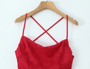 Détail d'une robe rouge avec motif feuille en relief et bretelles lacées sur cintre