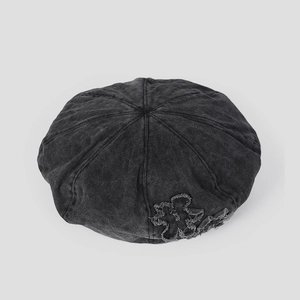 Detail of vintage washed denim beret featuring raw edge floral patch and retro stitching