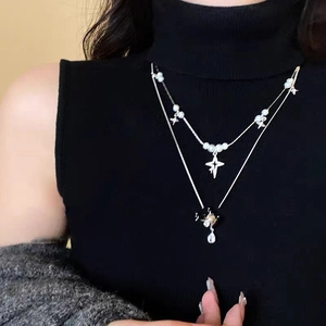 Layered pearl and starburst necklace set with black flower drop on black top
