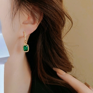 Nahaufnahme von Smaragd-Ohrringen mit Diamantbesatz, getragen von einem Model