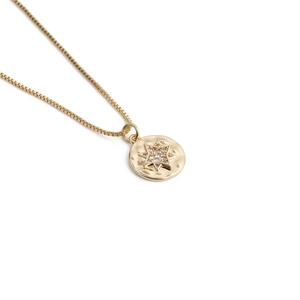 Detail of gold box chain necklace with hammered round pendant and sparkling star stone