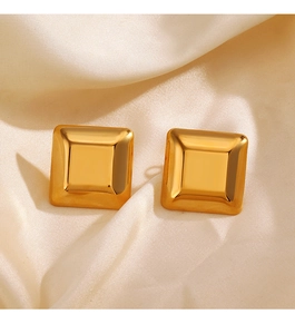 Detail shot of golden square stud earrings resting on smooth beige silk fabric surface