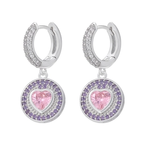 Détail macro de boucles d'oreilles argentées avec cœur rose et halo de cristaux mauves