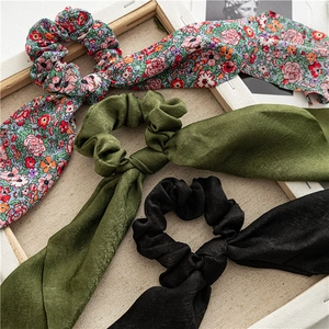 Close-up of three long ribbon scrunchies in floral, olive, and black matte satin fabrics