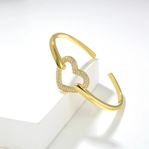 Dettaglio di bracciale a cuore dorato con pavé di zirconi su fascia minimalista