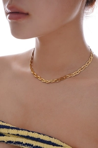 Detailed view of a triple-layered gold braided herringbone snake chain necklace on neck