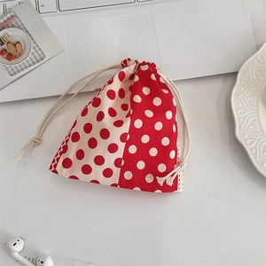 Close-up of red polka dot drawstring storage bag on a desk with lifestyle accessories