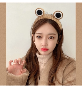 Close-up of cute knitted frog headband with big eyes on model for skincare and washing