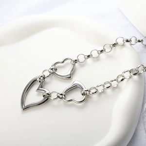 Detail of silver chain necklace with multiple hollow heart pendants on a white tray