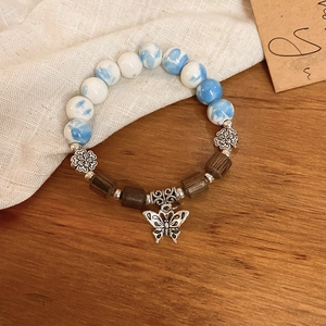 Detail of vintage ceramic beads and butterfly pendant on a handcrafted charm bracelet