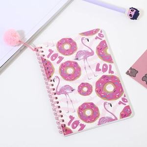 Detalle de cuaderno de espiral rosa con estampados de donuts y un suave colgante de pompón