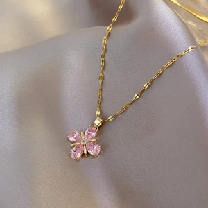 Elegant gold titanium steel necklace with pink four-leaf clover pendant on silk background