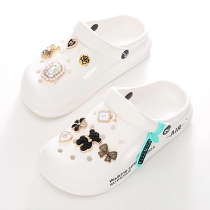 Detail of white platform clogs with bear, camellia flowers, and rhinestone charms