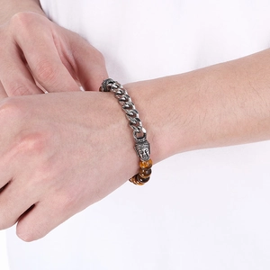 Close-up of tiger eye stone bracelet with silver Buddha head charm on person's wrist