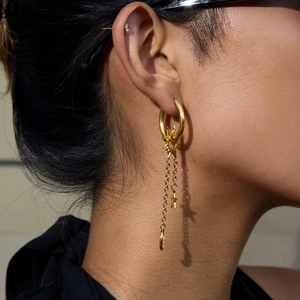 Détail de boucles d'oreilles dorées lune et étoiles avec éclairage latéral sur modèle