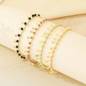 Detail of beaded bracelets with gold leaf charms in black, purple, green and pink colors