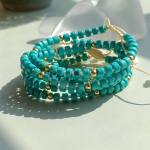 Close-up of bohemian multi-layered bracelet with turquoise beads and golden spacers