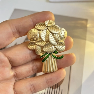 Gros plan sur une broche feuille en or mat avec nœud en émail vert et texture détaillée