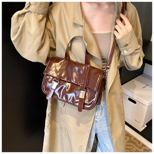 Detailed view of deep brown oily wax leather satchel bag worn with a khaki trench coat